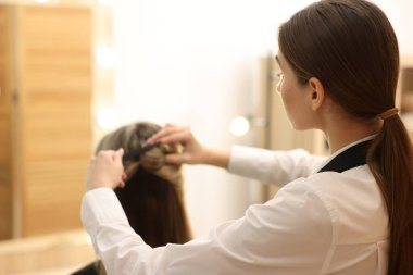 Kuaför kuaförde kadının saçına toka takıyor. Metin için boşluk