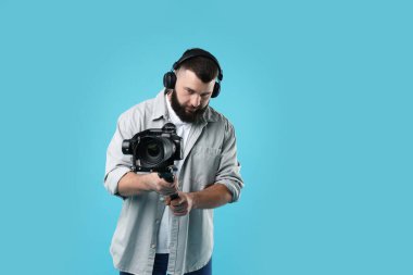 Açık mavi arkaplanda kameralı titreşim dengeleyici kullanan kameraman