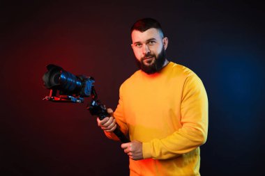 Kamerada çekim yapan kameraman, koyu arkaplandaki renk ışıklarına karşı titreşim dengeleyici kullanıyor.