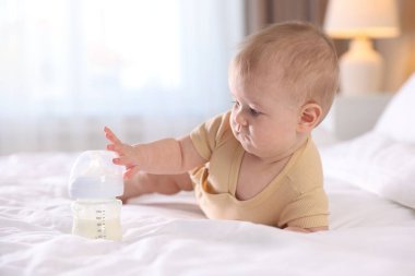 Evde yatağında biberonla beslenen tatlı bir bebek. Metin için boşluk