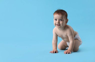 Açık mavi arka planda emekleyen şirin bir bebek.