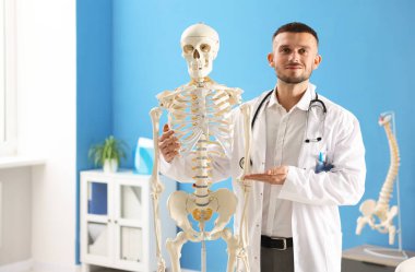 Doktor hastanede insan iskeleti modeli gösteriyor.