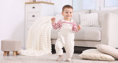 İlk adımlar. Evinde yerde yürüyen sevimli küçük bebek.