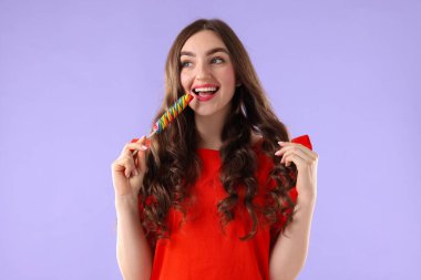 Menekşe arkaplanda lolipopu olan güzel bir kadın.