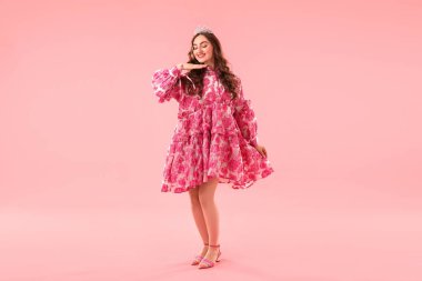 Pembe arka planda lüks bir taç giyen güzel kadın.