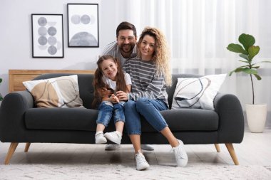 Mutlu ebeveynler evdeki kanepede kızlarına sarılıyorlar. Aile bağı