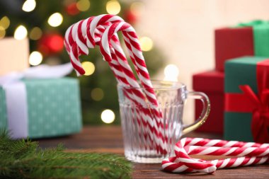 Kupada baston şekerler ve ahşap masada bulanık ışıklara karşı Noel süsü.