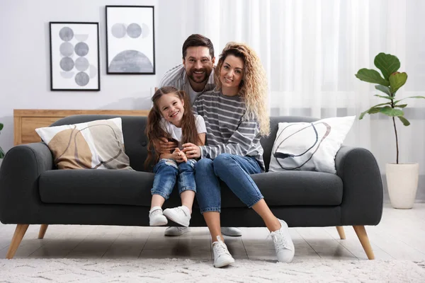 Mutlu ebeveynler evdeki kanepede kızlarına sarılıyorlar. Aile bağı