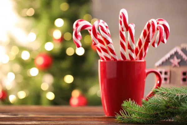 Bardakta şeker kamışı ve ahşap masada bulanık ışıklara karşı Noel süsü. Metin için boşluk