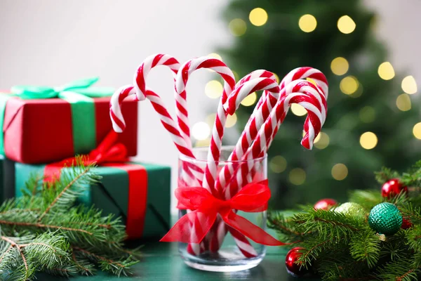 Cam çubuk şekerler ve yeşil ahşap masada bulanık ışıklara karşı Noel dekoru.