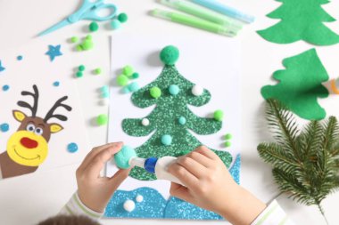 Küçük çocuk Noel kartpostalı hazırlıyor. Çocuk el yapımı.