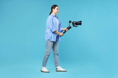 Açık mavi arkaplanda kameralı titreşim dengeleyici kullanan kameraman