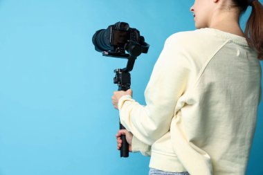 Açık mavi arkaplanda kamerası olan titreşimli dengeleyici kullanan kameraman, yakın plan. Metin için boşluk