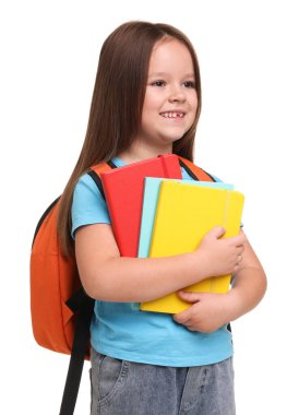 Beyaz arka planda defterleri ve sırt çantası olan sevimli küçük bir kız.