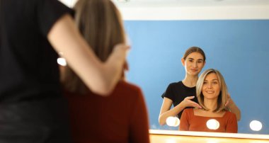 Kuaför, müşterisine kuaförde yeni saç kesimini gösteriyor.