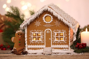 Güzel zencefilli kurabiye evi ve ahşap masanın üzerindeki Noel dekoru bulanık ışıklara karşı, yakın plan.