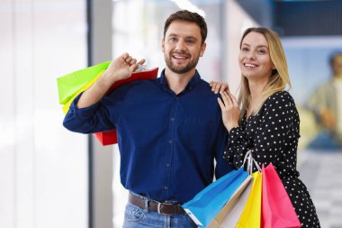 Alışveriş merkezlerinde farklı çantaları olan mutlu bir çift.