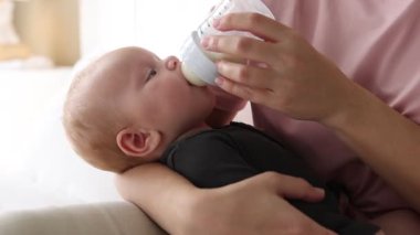 Anne bebeğini şişeyle besliyor.