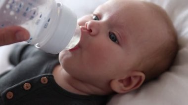 Anne bebeğini şişeyle besliyor.