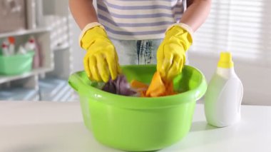 Beyaz masada plastik bir leğende çamaşırları yıkayan kadın, yakın plan. Kamera ileri gidiyor