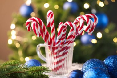 Bardaktaki şeker kamışları ve masadaki bulanık ışıklara karşı Noel süsü