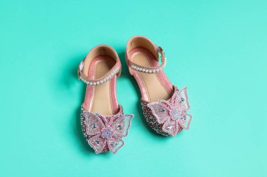 Turkuaz arka planda bir çift şık çocuk ayakkabısı.