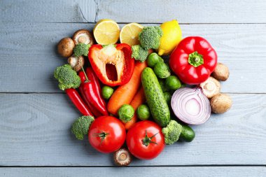 Gri ahşap masada taze taze sebzeler ve limonlar.