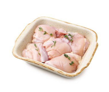 Çiğ tavuk butları ve kekik beyaz tencereye izole edilmiş pişirme kabında.