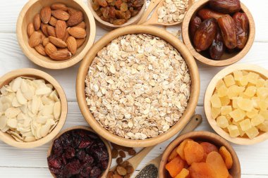 Tahıl yapıyorum. Yulaf gevreği, kurutulmuş meyve ve diğer malzemeler beyaz ahşap masa üzerinde, düz yatıyordu.