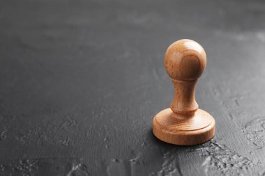 Koyu dokulu bir masa üzerinde bir tahta damga, yakın plan. Metin için boşluk