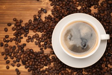 Aromatik kahve fincanda ve fasulye ahşap masada, düz yerde.