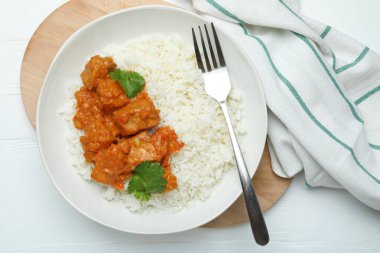 Pirinçli tavuk tikka masala, kişniş ve çatal beyaz ahşap masa, düz yatıyordu