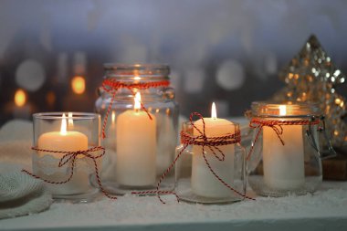 DIY Noel fenerleri. Cam kavanozlarda mum yakmak ve pencerenin pervazında yapay kar, yakın plan.