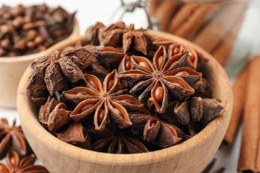 Sıcak şarap baharatları. Tahta kasedeki anason yıldızları ve beyaz masadaki tarçın çubukları, yakın plan.