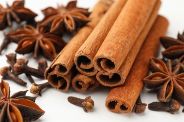 Sıcak şarap baharatları. Tarçın çubukları, anason yıldızları ve karanfiller beyaz ahşap masada, yakın plan