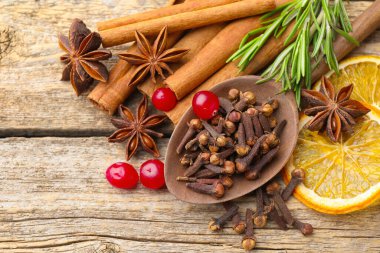 Farklı baharatlar, kızılcıklar, taze biberiye ve kuru portakal dilimleri ahşap masa üzerinde, düz yatıyordu.