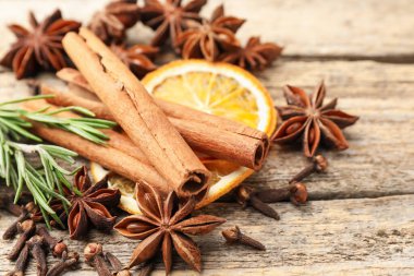 Farklı baharatlar, taze biberiye ve ahşap masada sıcak şarap için kuru portakal dilimleri, yakın plan.