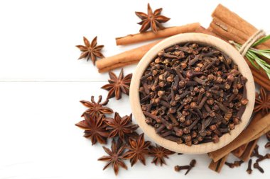 Sıcak şarap baharatları. Kasedeki karanfiller, anason yıldızları, tarçın çubukları ve beyaz ahşap masada taze biberiye, düz yatak. Metin için boşluk