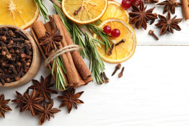 Farklı baharatlar, kuru portakal dilimleri, kızılcık ve taze biberiye beyaz ahşap masa üzerinde sıcak şarap, düz yatak. Metin için boşluk