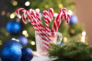 Bardaktaki şeker kamışları ve masadaki bulanık ışıklara karşı Noel süsü