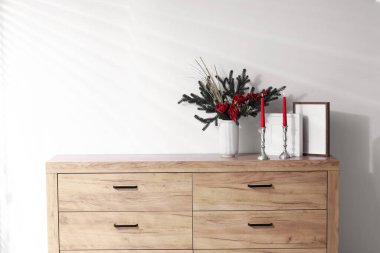 Beyaz duvarın yanındaki ahşap dolapta farklı bir Noel dekoru var.