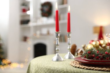 Noel dekorlu şenlik masası ve kapalı mekanda mum yakma, yakın çekim.