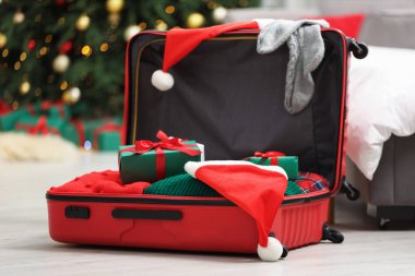 Noel tatili. İçinde Noel Baba şapkası, giysi ve hediye kutuları olan bavul.