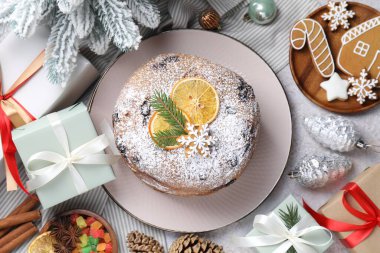 Lezzetli panettone keki, baharatlar, şekerli meyveler ve Noel süslemeleri gri masada, düz yatıyordu.