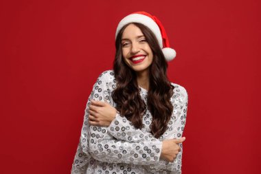 Kırmızı arka planda Noel Baba şapkalı güzel bir kadın. Noel sezonu