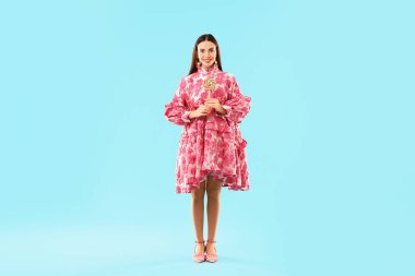 Açık mavi arka planda lolipopu olan güzel bir kadın.