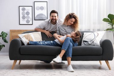 Mutlu ebeveynler ve kızları evdeki kanepede. Aile bağı