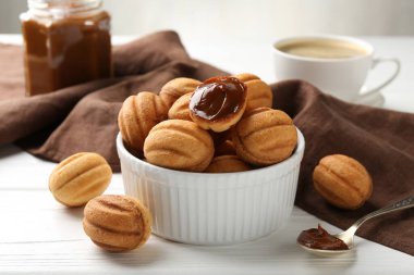 Lezzetli fındık şekilli kurabiyeler haşlanmış süt beyaz ahşap masada servis edilir, yakın plan.