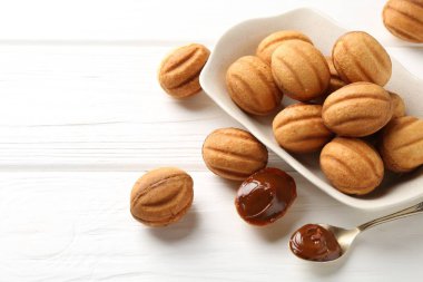 Lezzetli fındık şekilli kurabiyeler haşlanmış süt beyaz ahşap masada, yakın plan. Metin için boşluk