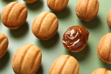 Lezzetli fındık şekilli kurabiyeler haşlanmış konsantre süt yeşil arka planda, yakın plan